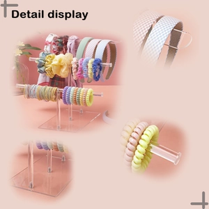 Detailed close-up of a three-tier clear acrylic display stand with colorful hair accessories