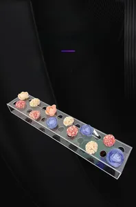 Macro detail of a rectangular acrylic vase with multiple holes and colorful silk flowers