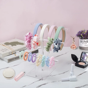 Three-tier clear acrylic headband holder with scrunchies and hair accessories on desk