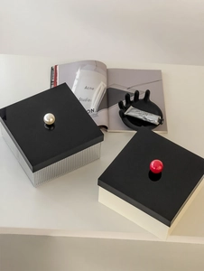 Detail of acrylic storage box featuring a pearl handle and a red sphere handle design