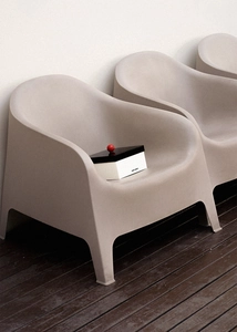 Minimalist greige armchair with a decorative storage box on a wooden patio