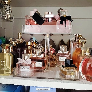 Close-up of a clear 2-tier acrylic display stand for organizing luxury perfume bottles