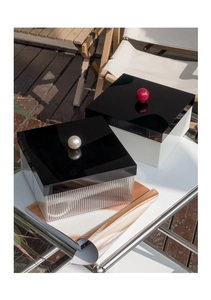 Detail view of retro acrylic storage boxes with pearl and red ball handles on glass table