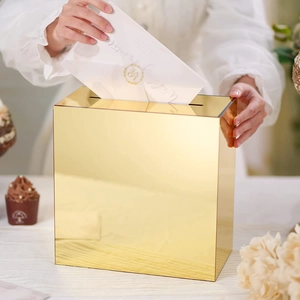 Macro view of person placing card into mirror gold acrylic wedding card box with slot