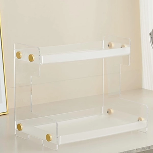 Close-up of a double-tier clear acrylic shelf with elegant gold metal support accents
