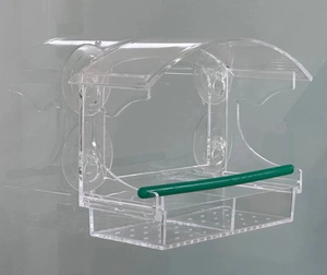 Macro view of transparent acrylic bird feeder with suction cups and green perch stand