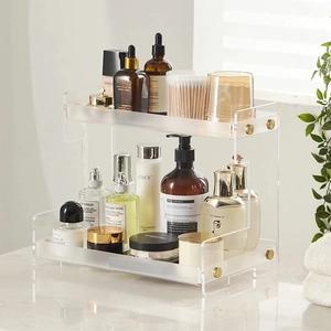 Detail of a two-tier clear acrylic vanity organizer with gold metal screw accents