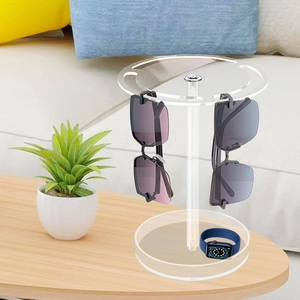 Rotating acrylic sunglasses holder on a wooden table in a cozy living room setting