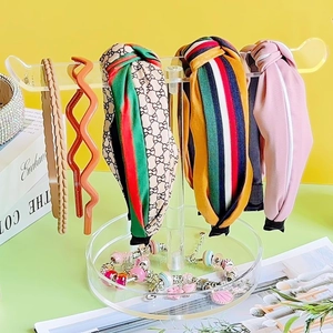 Clear acrylic headband stand displaying assorted stylish fabric and woven hair hoops