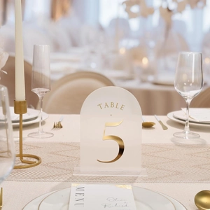 Close-up of frosted arched acrylic table number 5 with gold mirror finish and clear base