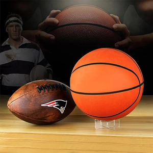 Detail view of acrylic ball stands supporting a basketball and NFL branded rugby ball
