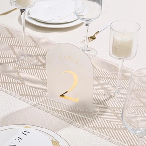 Detail of frosted arch acrylic table number with gold foil text for wedding decor
