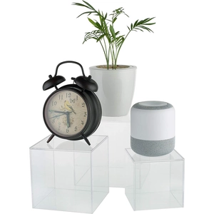 Clear acrylic display cubes with polished edges holding home decor items on white background