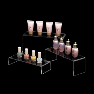 Three-piece clear acrylic tiered display risers for retail items on a black background