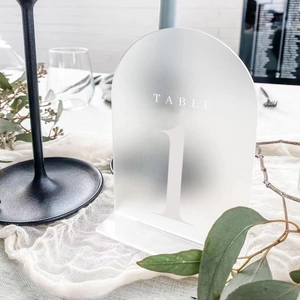 Detail view of frosted acrylic arch table number with white printed Table 1 lettering