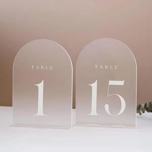 Close-up of frosted arched acrylic wedding table numbers with elegant white printing