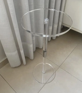 Detail of a minimalist clear acrylic side table with a round top and cylindrical base