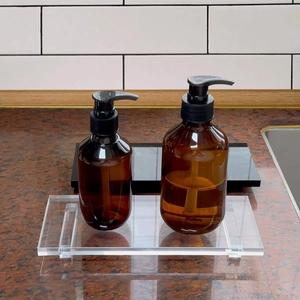 Close-up of amber dispenser bottles with black pump heads on a clear acrylic tray