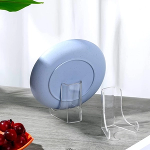 Clear acrylic easel stand holding a blue decorative plate on a grey wooden desk