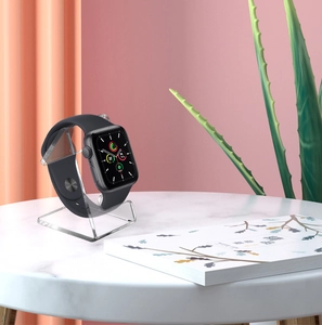 Smartwatch with black silicone band on transparent acrylic stand atop marble table