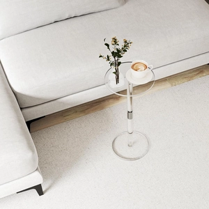 Close-up of minimalist clear acrylic side table with polished silver metal joint