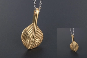 Macro detail of golden feather pendant showing fine vein textures and two-tone metal finish