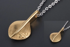 Close-up detail of golden leaf feather pendant with intricate vein texture and silver chain