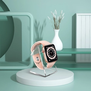 Smart watch with pink strap on a minimal display stand in a modern mint green studio
