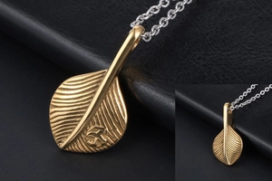 Detailed close-up of golden leaf pendant with intricate veins on black leather texture