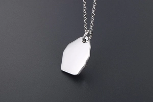 Macro shot of silver irregular geometric pendant with polished mirror finish and link chain