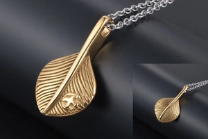 Detail of golden feather pendant with embossed bird motif on a silver steel chain