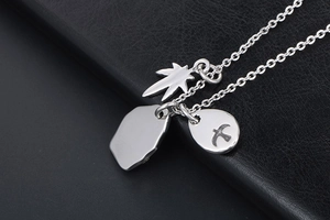 Detailed close-up of silver punk necklace featuring maple leaf and flying bird pendants