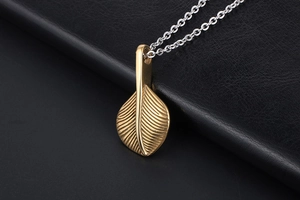 Macro detail of golden feather pendant with radiating texture on a silver chain link