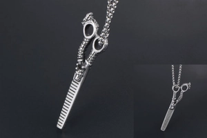 Macro detail of stainless steel dragon patterned barber scissor pendant on bead chain