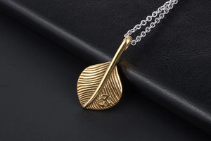 Macro detail of golden feather pendant with intricate veins on black leather