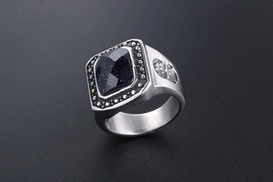 Macro detail of men's vintage steel ring featuring faceted blue sand stone and side skull carvings