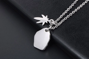 Macro shot of silver eagle pendant with leaf detail on black textured leather