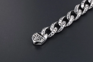 Macro view of stainless steel chain links with intricate dragon scale textures and antique finish