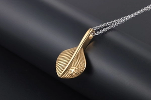 Detailed close-up of a vintage golden feather pendant with eagle motif on silver chain