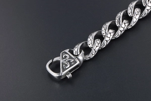 Macro detail of retro stainless steel chain with heart textured links and engraved lobster clasp