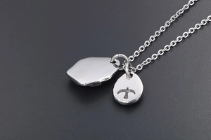 Detailed view of silver eagle pendant and oval charm on polished stainless steel chain