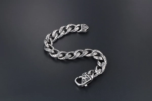 Macro detail of men's vintage silver curb chain with textured links and carved buckle