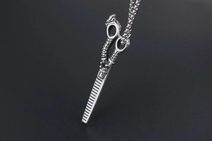 Macro detail of silver dragon embossed hairdressing scissor pendant with square chain necklace