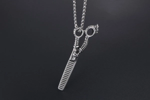 Macro detail of stainless steel hair stylist necklace with dragon scissor and comb pendant