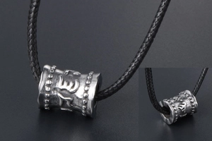 Détail macro du pendentif cylindre avec écritures gravées et finition en acier vintage