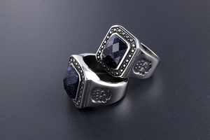 Close-up of vintage steel ring with blue sandstone inlay and skull carvings on side