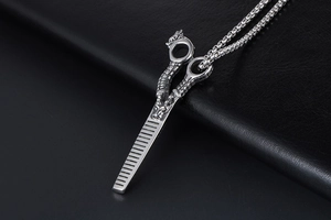 Macro detail of silver dragon barber comb pendant with box chain on black leather