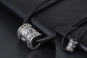 Macro shot of titanium steel cylinder pendant with sacred mantra and woven black cord