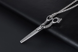 Macro detail of stainless steel barber scissor and comb pendant with dragon texture