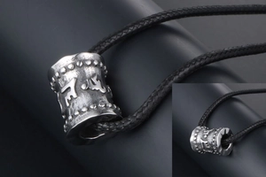 Vue détaillée du pendentif cylindrique en acier titane vintage avec mantra bouddhiste gravé